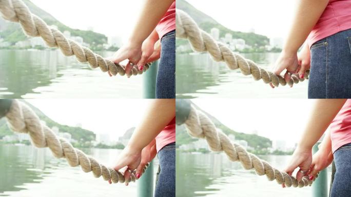 夫妇的手在巴西湖边的绳子上