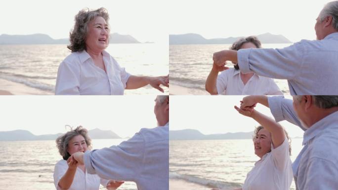 亚洲资深夫妇在沙滩上跳舞，一起大笑。有生活方式、情感和退休观念的人。慢动作镜头。