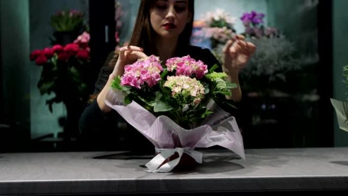 花店里的女花店照顾装满粉红色纸的小花。