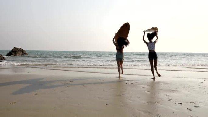 两个带冲浪板的女孩在海滩上玩得开心