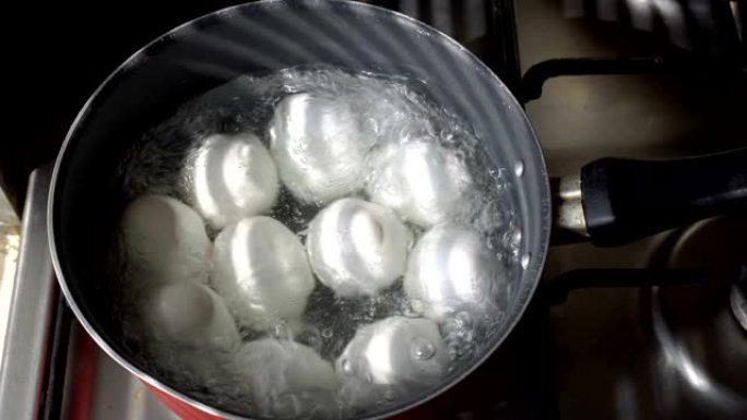 白鸡蛋在煤气炉上的锅里用沸水煮沸。特写。从顶部看。4K。