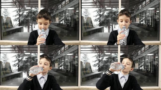 一个男生坐在桌子旁，咀嚼并从塑料瓶中喝水