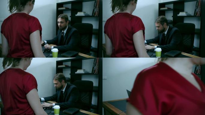 大胡子的商人坐在办公室的笔记本电脑上，穿红色衣服的女孩试图引诱老板，慢动作