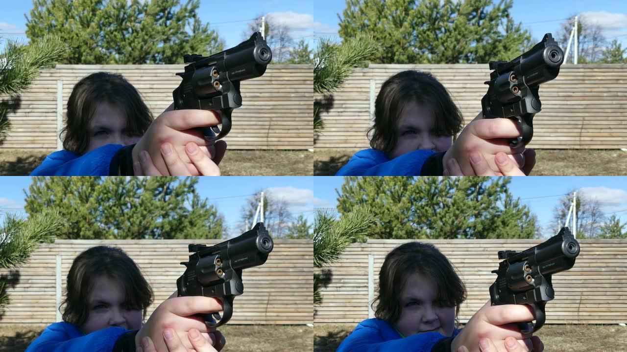 一个拿着枪的少年暗示了一个目标。少女射击气动手枪。手握气动左轮手枪。特写。