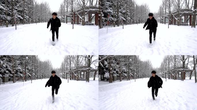 斯洛莫-快乐的亚洲年轻人在下雪时在公园跑步