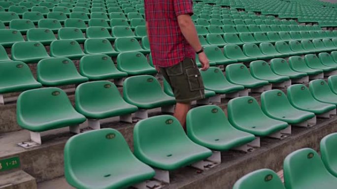 体育场的一名男子坐在观看区的椅子上