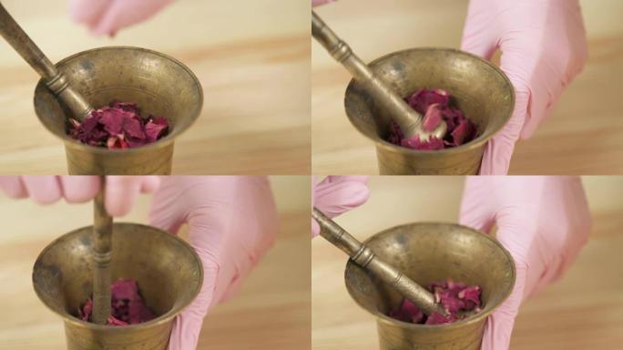 特写镜头，一个女孩用杵在铜研钵中磨碎了干燥的玫瑰花瓣。