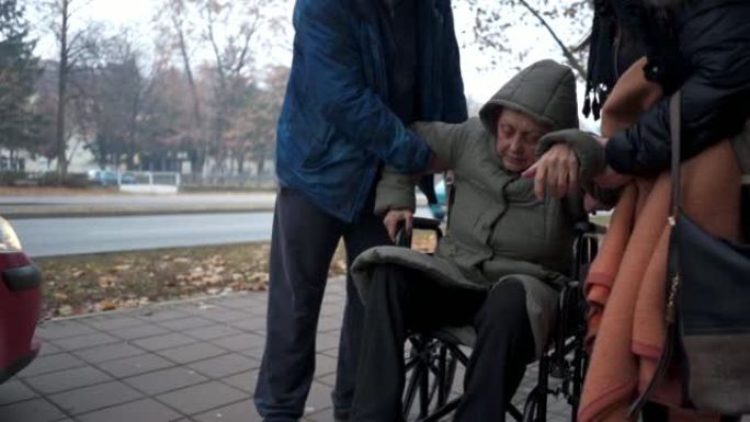 儿子和女儿帮助年长的母亲从轮椅上站起来