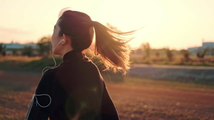 带着耳机在日落时间跑步的女人 (慢动作)