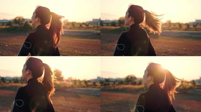 带着耳机在日落时间跑步的女人 (慢动作)