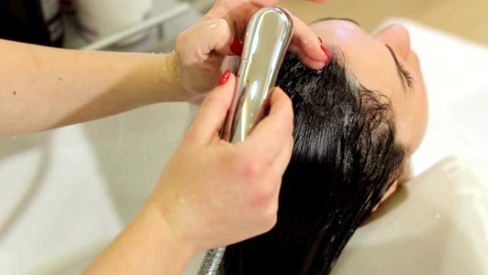 美发师在美容院理发前洗一个年轻女孩的头发。