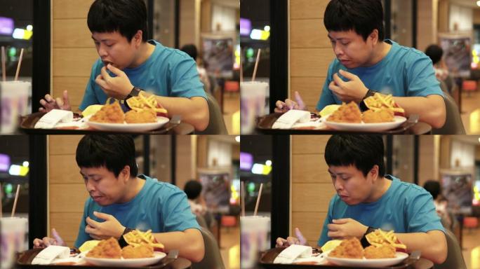 亚洲男子坐在咖啡馆吃薯条。