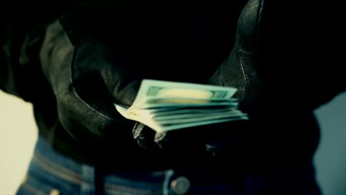 戴着黑手套的男人拿着一堆钱，犯罪概念