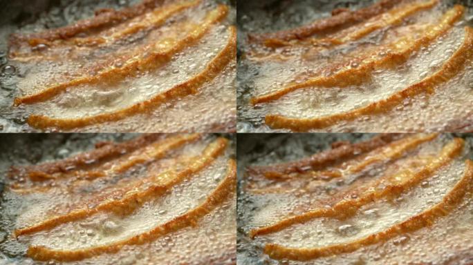 4k视频选择性聚焦稳定特写微距拍摄新鲜自制油炸脆脆猪肉肚在煎锅中煮沸的棕榈油中。