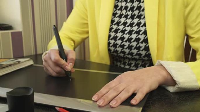一个穿黄色夹克的女孩在平板电脑上画画