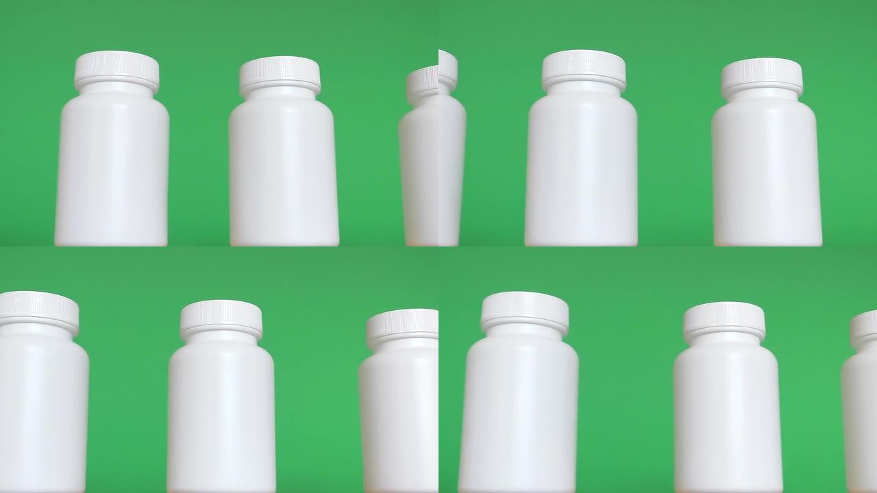 一排白色瓶子在绿色背景下隔离