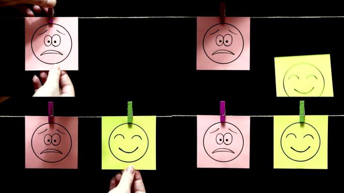 两张贴纸。情绪。面对沮丧的表情。面对微笑和友好的布局。用绳子上的衣夹手动连接床单。黑色背景。