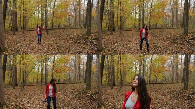 女人拿着相机在秋天的森林里散步