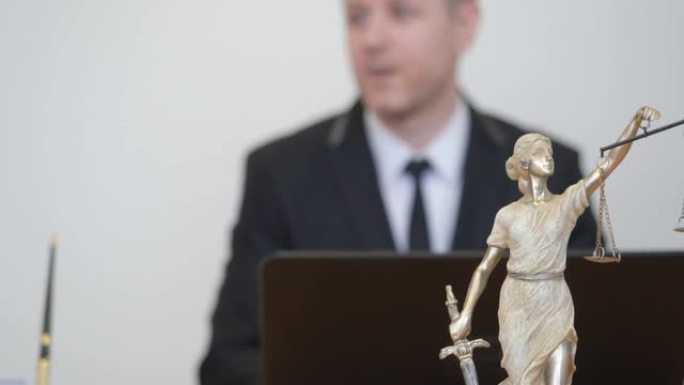 男人和女人咨询专业律师。律师事务所的Themis雕像