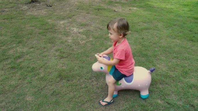 可爱的金发小男孩骑着马玩具独角兽