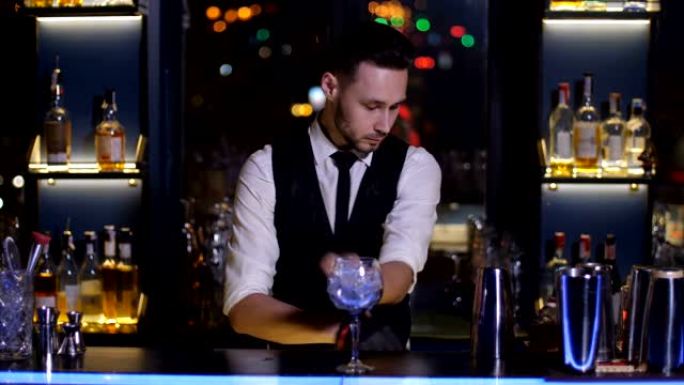 酒保在酒吧将冰放入玻璃杯中制作鸡尾酒