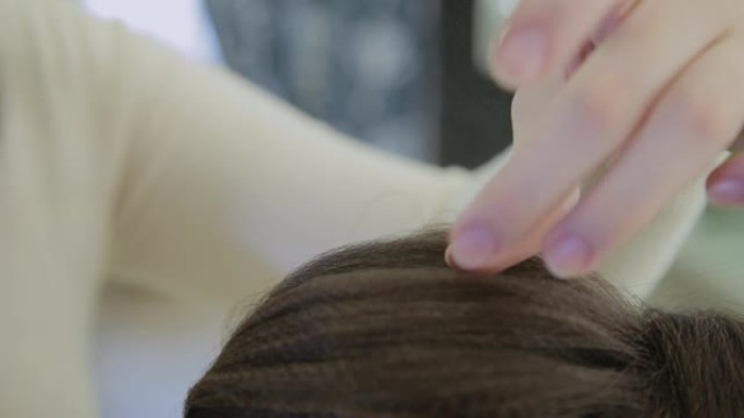 一名年轻女子坐在美发师的扶手椅上: 美发师进行发型设计。一位年轻的金发女子来到美容院做时尚的发型