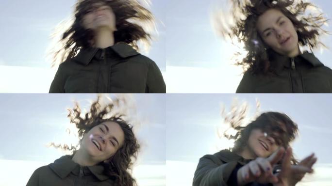 一个美丽的微笑年轻女孩的肖像，卷发的黑发在户外阳光下跳跃