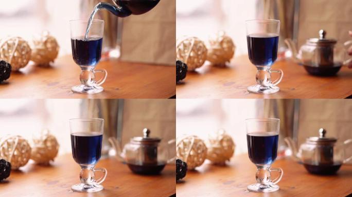 咖啡馆桌子上的花阴蒂上的蓝蝴蝶豌豆茶。花蓝泰国茶倒入透明杯子中。减肥、健康、排毒茶