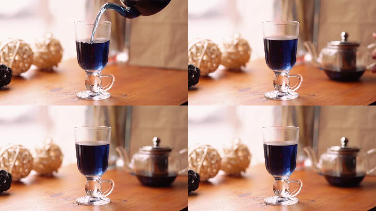 咖啡馆桌子上的花阴蒂上的蓝蝴蝶豌豆茶。花蓝泰国茶倒入透明杯子中。减肥、健康、排毒茶