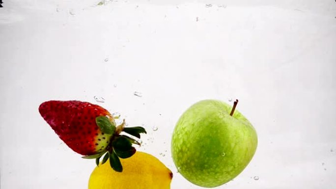 草莓，柠檬和苹果在水中以慢动作旋转的气泡旋转。