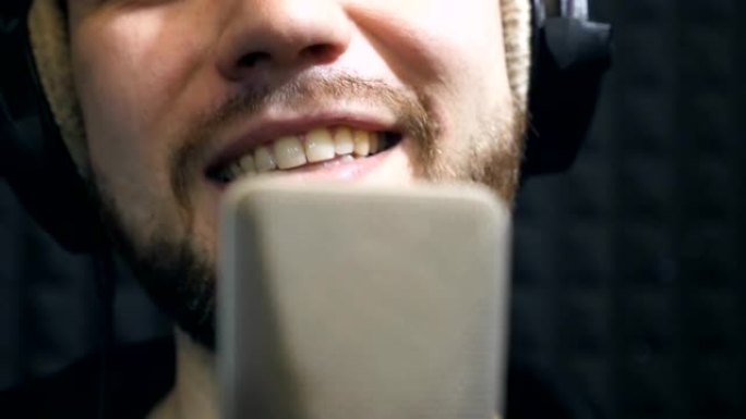 耳机男歌手在sound studio的麦克风中唱歌。年轻人在情感上录制新的旋律或歌曲。创意音乐家的工