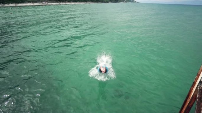 年轻人跳入绿松石海水，慢动作