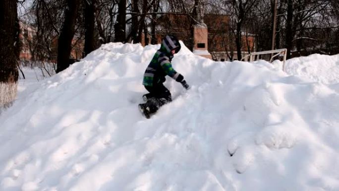 男孩在雪地里玩耍。从雪山上下颠倒地滑落。