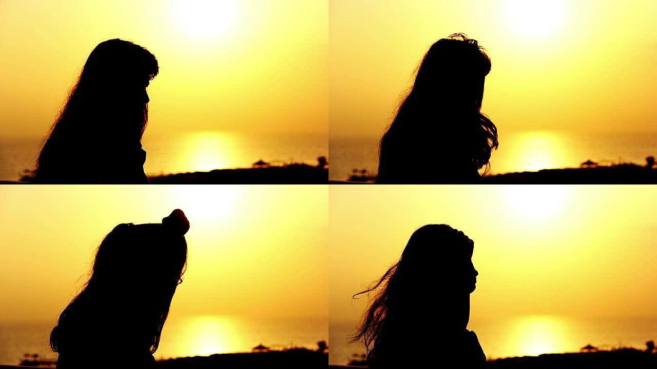 日落时分，一个女人的剪影在海边拉直了头发在阳台上