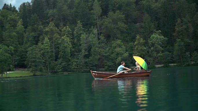 船上两个人划船一个拿着五颜六色的伞