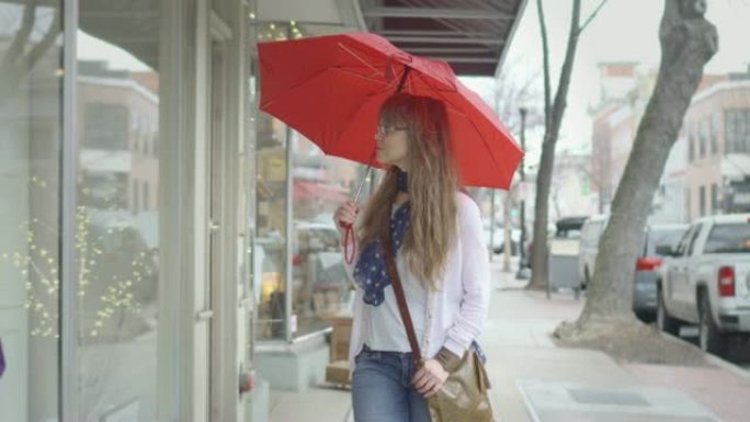 手持红伞的美女在雨中行走