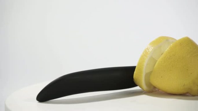 黄色柠檬和小刀放在白色木桌上，旋转360度。白色背景。
