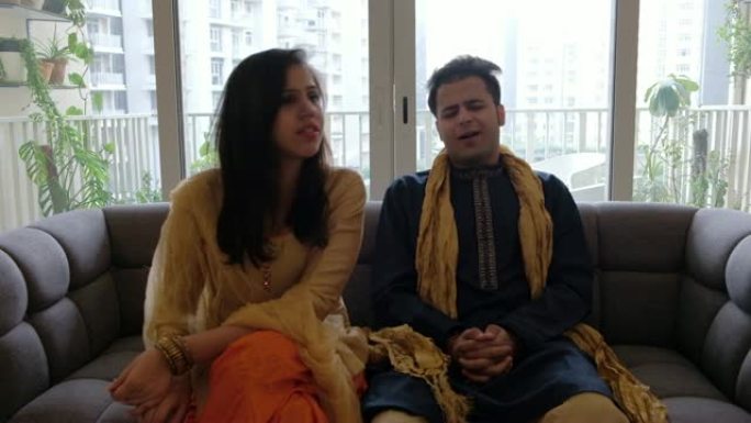 印度夫妇坐在沙发上，穿着传统服装与相机外的人交谈