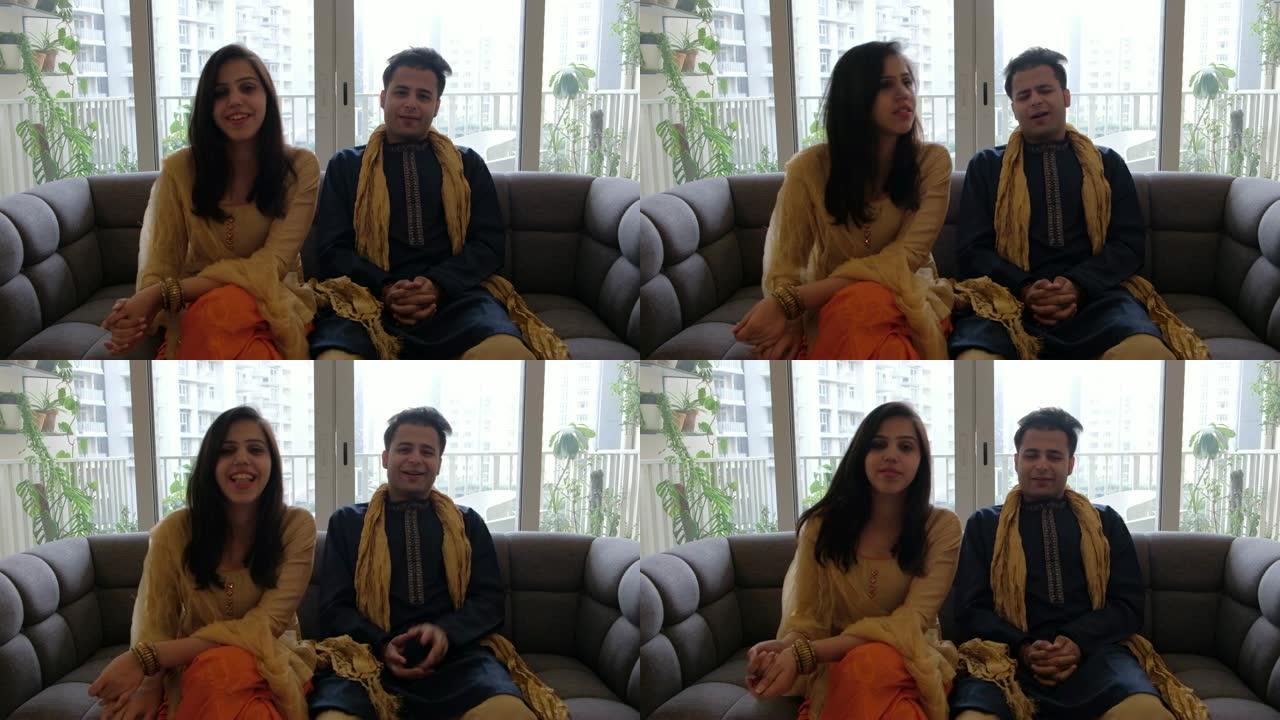 印度夫妇坐在沙发上，穿着传统服装与相机外的人交谈
