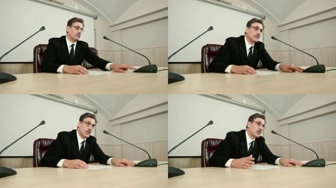 新闻发布会上，发言人按下桌面麦克风按钮，回答记者提问。