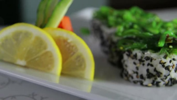 美味的寿司卷在盘子上装饰有芥末、生姜、柠檬和海藻
