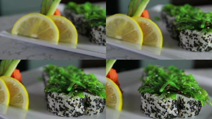 美味的寿司卷在盘子上装饰有芥末、生姜、柠檬和海藻