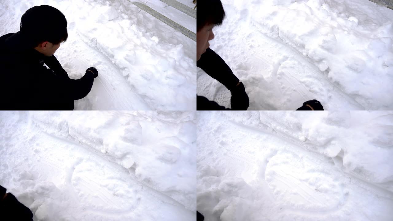 年轻人用手指在雪地里画心