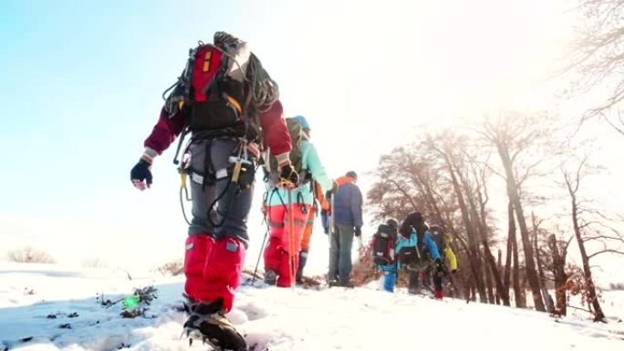 装备精良的登山者在大雪中相互跟随，从后面可以看到风景。