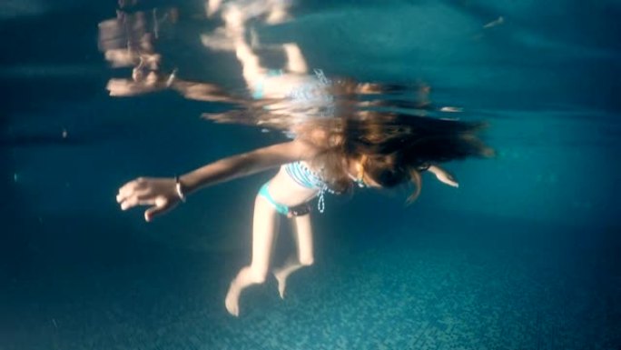 淹没女孩在黑暗的游泳池表面，水下景观