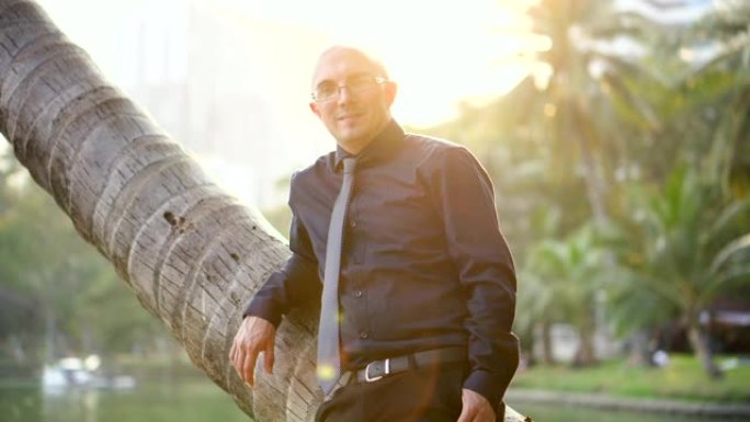 约会网站广告-自信的英俊男人靠在棕榈树上微笑着对着镜头