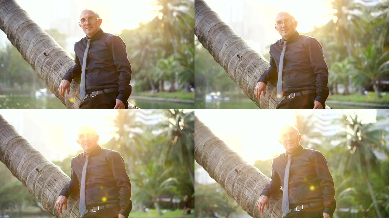 约会网站广告-自信的英俊男人靠在棕榈树上微笑着对着镜头