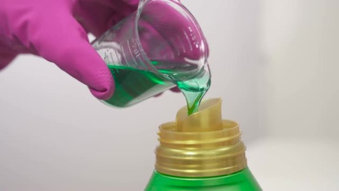 一个女人将洗涤剂从量杯倒入瓶子的特写镜头