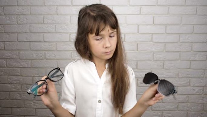儿童拿着两种类型的眼镜。