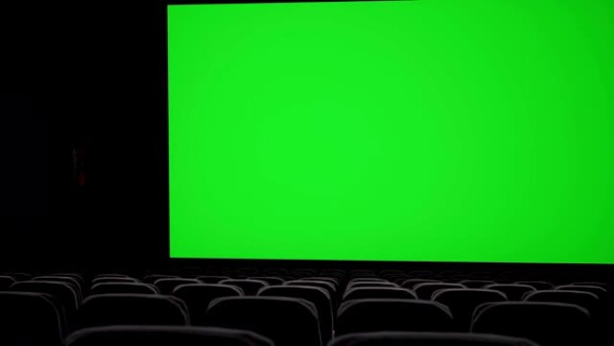 电影院内部，带空白电影院屏幕，带绿屏和空座位。电影娱乐概念。